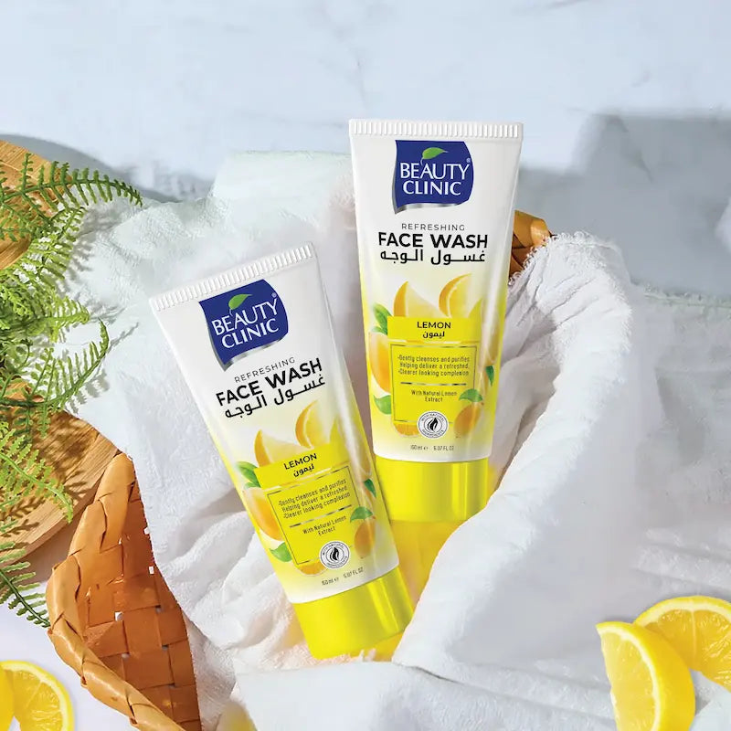 Two tubes of Beauty Clinic Lemon Face Wash arranged in a woven basket with white towels and lemon slices on a light marble-like surface.