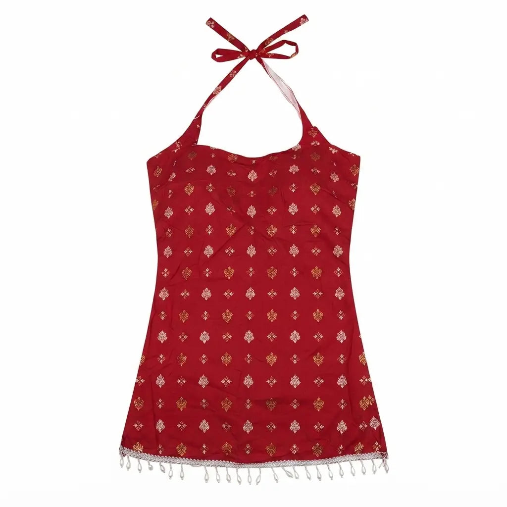 A red halter-neck top with a small repeating gold and white pattern, featuring white tassel fringe along the hem and tie straps, shown against a plain white background.