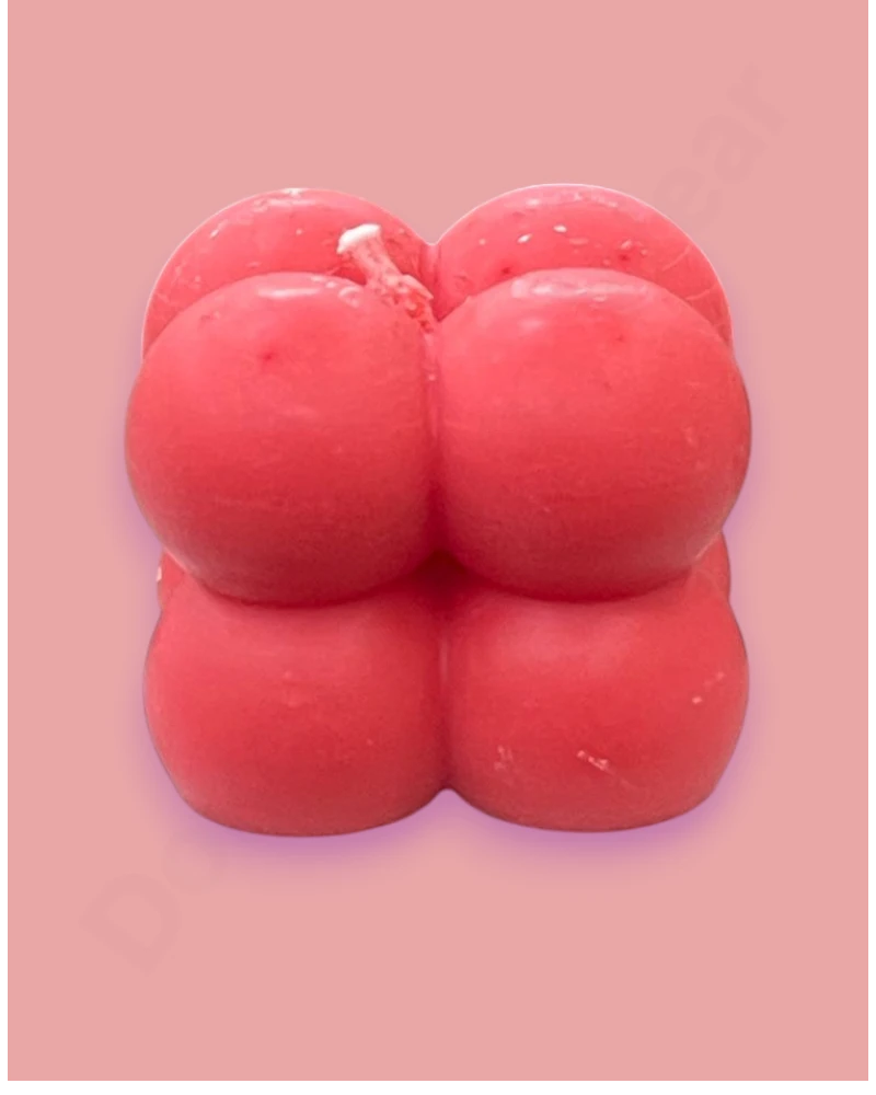 Red candle shaped like a stylized face on a pink background