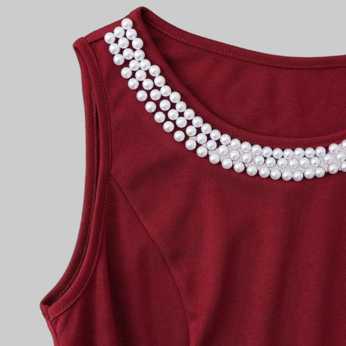 Red sleeveless top with pearl embellishments on a beige surface