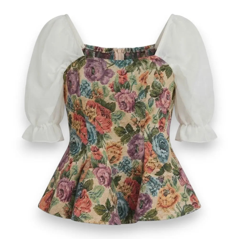 A vintage-style floral dress top featuring a peplum waist, a beige background with a colorful rose and floral pattern, and contrasting white puff sleeves with ruffled cuffs.