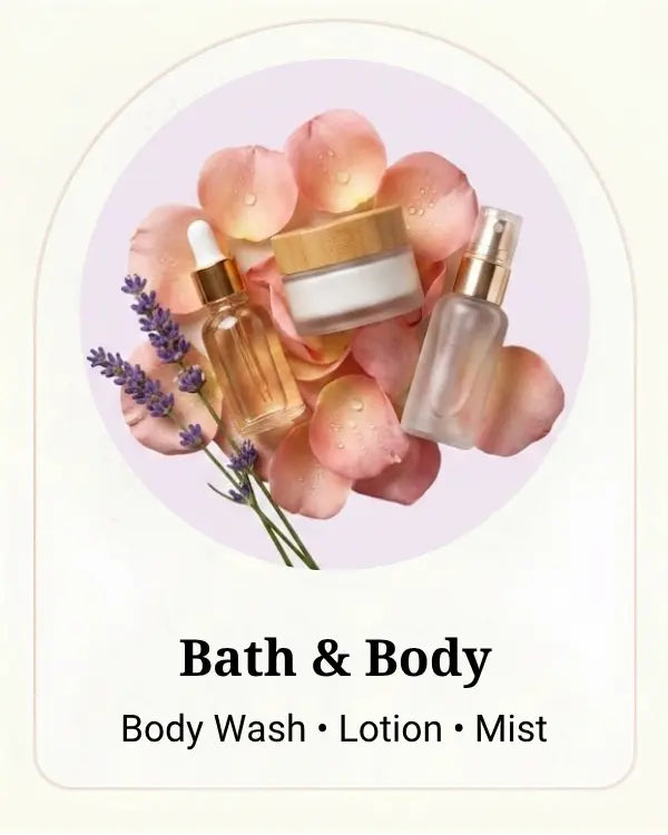 A set of bath and body products including a body wash dropper bottle, a lotion jar with a gold lid, and a mist spray bottle, arranged on pink rose petals with lavender sprigs inside an arched oval frame. Text below reads 'Bath & Body' and 'Body Wash • Lotion • Mist'.