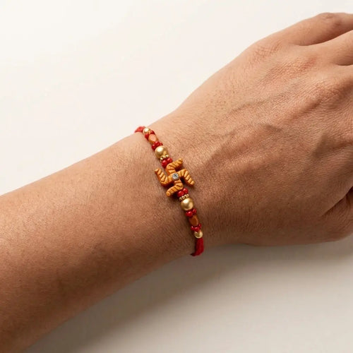 Traditional Swastika Rakhi with Red & Gold Beads